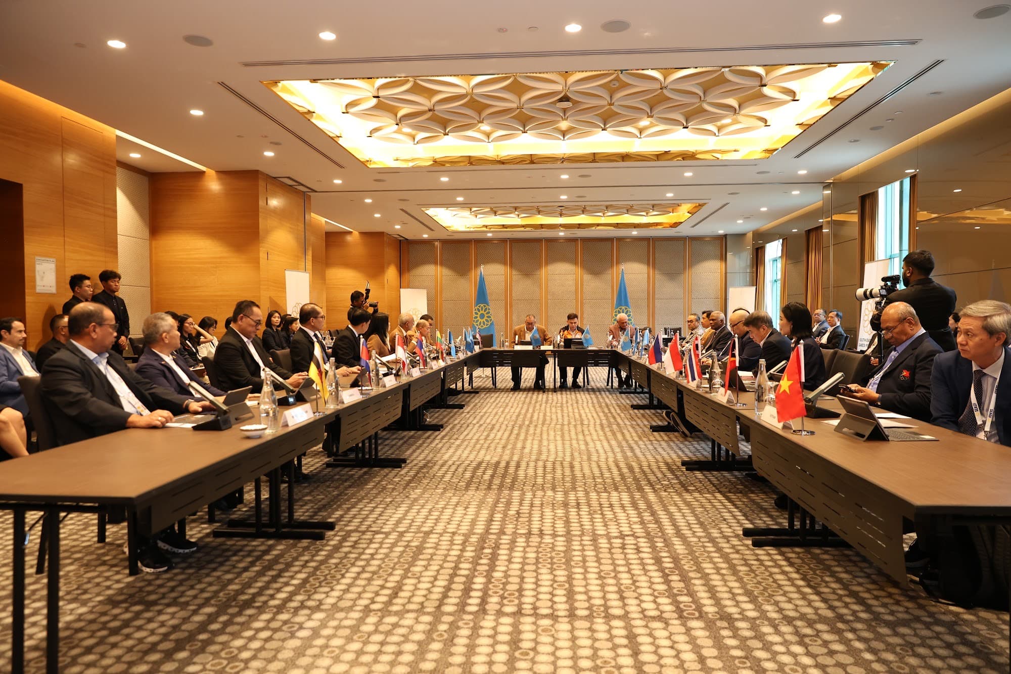 A SEAGF committee session in a U-shaped hall, with national flags along the tables.
